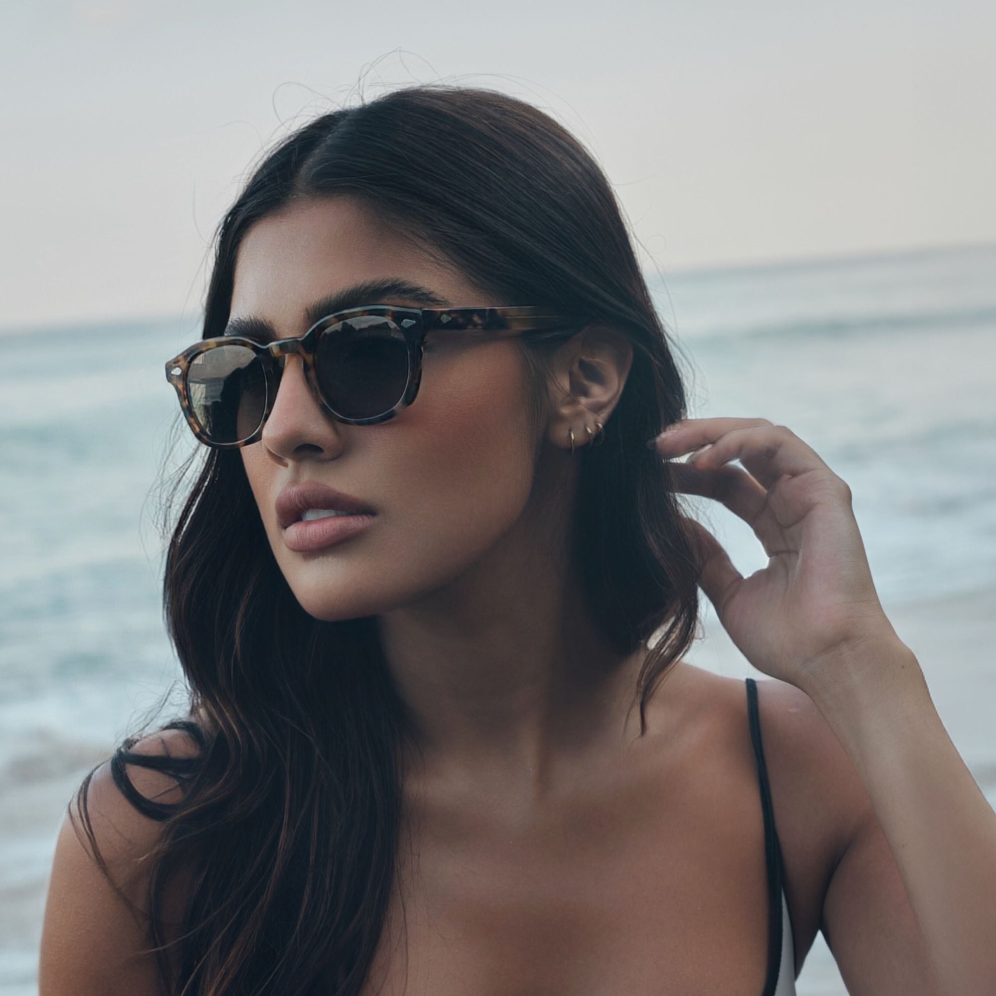 Woman wearing sunglasses with a blurred ocean background